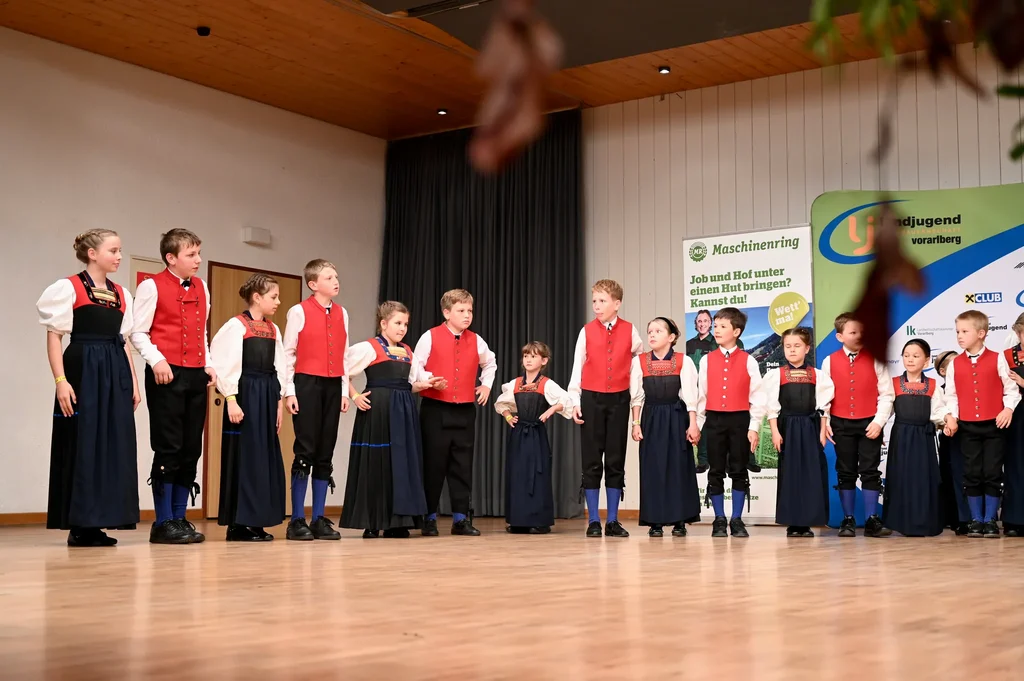 Die Kindertrachtengruppe Hittisau steht in einer Reihe auf der Bühne im Dorfsaal Alberschwende