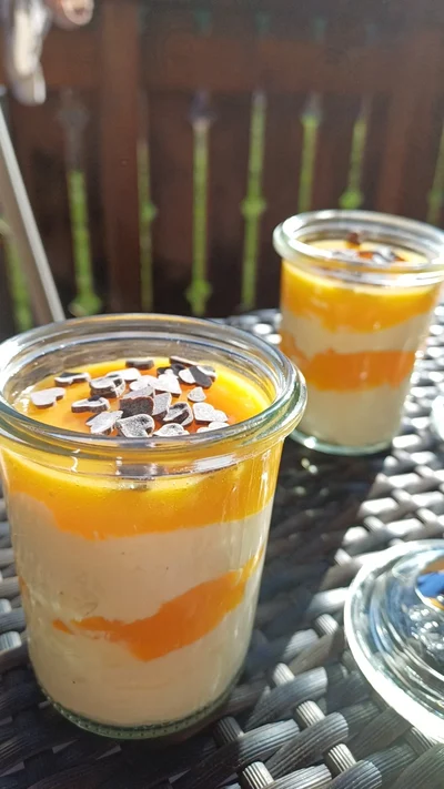 Zwei Dessertgläser mit Creme und Fruchtspiegel, verziert mit kleinen Schokoherzen