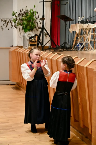 Zwei Mädchen in Tracht stehen am Bühnenrand, eine klatscht in die Hände