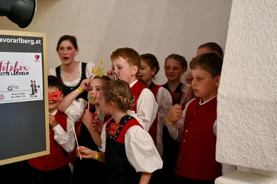 Kinder der Trachtengruppe posieren mit Papiermasken und einer Pappkrone vor der Fotobox