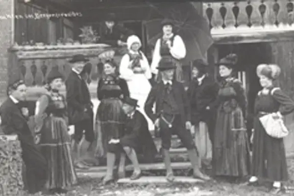 Historische Aufnahme: eine Gruppe in Tracht vor einem Bregenzerwälder Haus