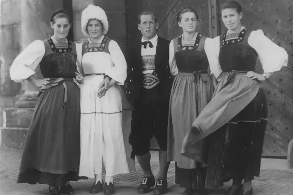 Historische Aufnahme: Trachtenträgerinnen und Trachtenträger vor einem Kirchenportal